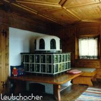 Individueller Kachelofen in München: Der rustikal bäuerliche Stubenofen ist in einem grünen Farbton glasiert. Als Kombiofen versorgt er das Wohnzimmer mit Warmluft und die Stube mit Strahlungswärme
