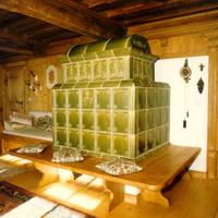 Individueller Kachelofen in München: bäuerlicher Kachelofen in grün, Flaschengrün glasiert. Die traditionelle Bauweise als Grundofen sorgt für eine lange Wärmespeicherung